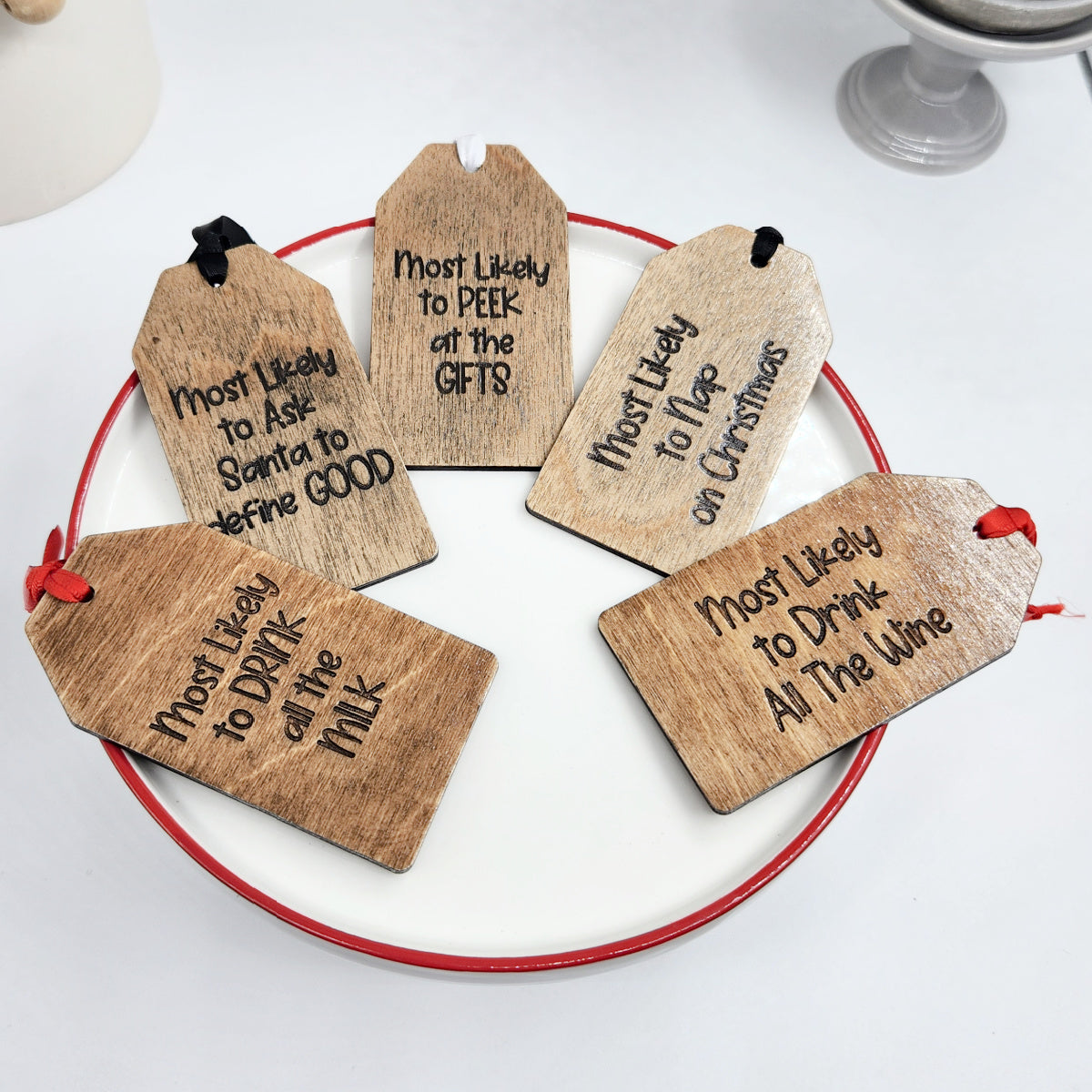 Wooden Christmas tags with humorous inscriptions on a white surface.